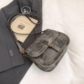 Vintage smoke gray saddle bag with distressed texture and metal buckle on bed linen - Carbon Gray
