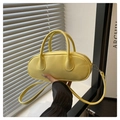 Detalle de un bolso baguette amarillo brillante con asas cilíndricas y cremallera de metal - Amarillo