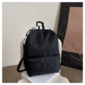 Detail of minimalist black nylon backpack with white lettering on top and large front pocket - Black