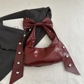 Dark red underarm bag featuring a large bow with silver studs and glossy leather finish - Red