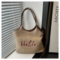 Dettaglio del ricamo Hello rosso su borsa tote in paglia beige con manici in pelle - Cachi