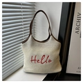 Dettaglio della borsa tote intrecciata crema con ricamo Hello rosso e manici in cuoio - Bianco Sporco