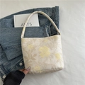 Elegante borsa tote crema con ricamo floreale su sfondo di giacca di jeans - Beige