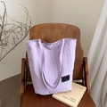 Bolso bandolera minimalista de nailon lavanda sobre una silla de madera vintage - Morado