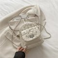 White quilted mini backpack with silver rivets and metal chain straps in a flat lay - White