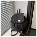 Detalle de mochila con patrón de rejilla, cierre de cordón y hebilla plateada bajo luz natural - Negro