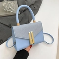 Light blue crossbody bag with textured flap and golden H buckle in a stylish setting - Blue