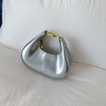Close-up of metallic silver hobo bag featuring gold buckle detail and zipper texture - Silver