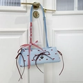 Light blue baguette bag with red bow print and lace trim hanging on a white door - Blue