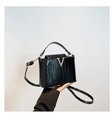 Gros plan du sac à main noir à texture crocodile avec boucle en métal doré en forme de V - Noir
