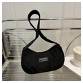 Detail of black corduroy crescent bag with FASHION INSTINCT tag on a modern chair - Black