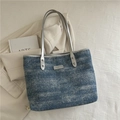 Blue denim texture tote bag with silver handles and metallic logo plate for daily commute - Blue