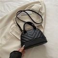 Elegante bolso de mano negro acolchado en V con herrajes dorados y asas dobles sobre traje - Negro