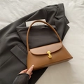 Minimalist caramel brown shoulder bag with gold oval clasp on a grey blazer suit - Brown