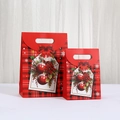 Detail van kerstcadeautassen met rood geruit patroon, bloemenprints en feeststrikken - 20x16x7cm