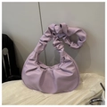 Detalle del bolso de mano morado plisado en piel sintética sobre tela blanca - Morado