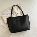 Minimalistische große schwarze Shopper-Tasche mit Fashion-Tag auf weißem Stoff - Schwarz