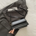Minimalist black flap crossbody bag with adjustable strap on gray background - Black