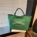 Large green tote bag with white lettering and black white rope handles on window sill - Green