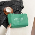 Green high-capacity tote bag with letter print and woven handles in a lifestyle setting - Green