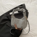 Silver pleated cloud handbag with hobo design and gold hardware shown on black suit jacket - Gray