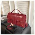 Detail der dunkelroten Lackledertasche mit Goldbeschriftung und Zierschnallengurt - Rot
