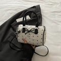 White seersucker Boston bag with black bows and heart pendant on gray blazer - White