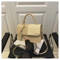 Dettaglio della borsa beige in ecopelle e paglia intrecciata su dei libri - Cachi