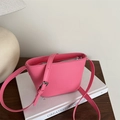 Pink PU leather crossbody square bucket bag with embossed logo on a wooden desk - Pink