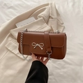 Brown leather crossbody bag featuring silver metal bow and stylish chain strap - Brown