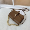 Borsa a tracolla marrone in pelle con chiusura dorata e catena su sfondo di tessuto - Marrone