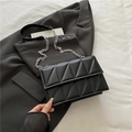 Chic black quilted crossbody chain bag with geometric triangular pattern on grey suit - Black