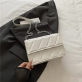 White quilted rectangular crossbody bag with silver chain strap on a black blazer - White