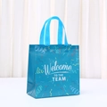 Dettaglio della borsa regalo blu in TNT con scritta Welcome TO THE TEAM e nastri colorati - Stile Nastro Meteora Blu (1011-2)