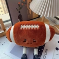 Peluche a forma di football americano con viso sorridente e scarpe in un ambiente caldo - Palla da rugby