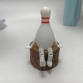 Articulated bowling pin figurine in sitting pose on a natural wood stump base - Bowling Pin Style