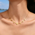 Detail of seven gold daisy pendants on a stainless steel necklace worn by a model - 7 Daisy Flowers