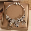 Silver charm bracelet with golden snitch clasp and wings pendants on a jewelry box - Dreamcatcher Wing Bracelet