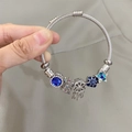 Silver charm bracelet with blue stone charms, dreamcatcher and star on steel cord - Blue Windmill Dreamcatcher Bracelet