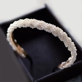 Dettaglio di un elegante cerchietto con fitte perle bianche e bordi metallici dorati - Stile 1 Intrecciato