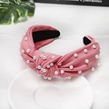 Detailed view of pink knotted headband with white pearls on a ribbed knit fabric - Watermelon red