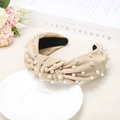 Elegant apricot knotted fabric headband with white pearl accents on ceramic tray - Khaki