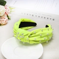 Detail of neon green knotted headband with pearls on white ceramic plate and magazine - Fluorescent Green