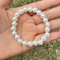 Close-up of white faux pearl bracelet for girls held over a natural grass background - 8MM Cream White Pearl Bracelet