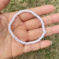 Detailed view of elastic white faux pearl beaded bracelet on hand with outdoor background - 4MM Pure White Pearl Bracelet