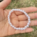 Close-up of white imitation pearl bracelet on palm with blurred outdoor background - 6MM Pure White Pearl Bracelet