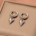 Detailed close-up of silver heart dangle earrings with polished stainless steel finish - Silver