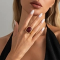 Statement gold-tone ring with a large oval dark red gemstone and braided metal border - Light Gold + Wine Red (00986)