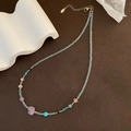 Light blue beaded necklace with colorful stones and gold hardware on brown background - Purple Pink Colorful Crushed Stone and Light Blue Bead Necklace (03-J 23)