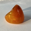Macro shot of an amber acrylic ring featuring a polished triangular top on a white surface - Orange(32358)